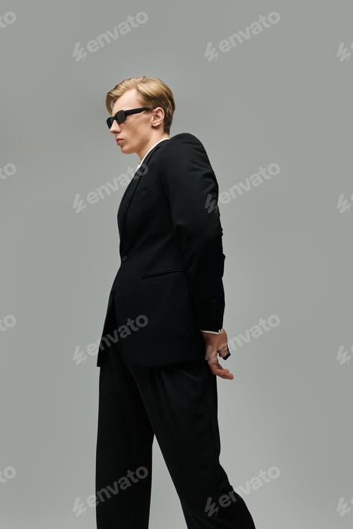 Preview: Young handsome man in stylish suit posing confidently against a neutral backdrop