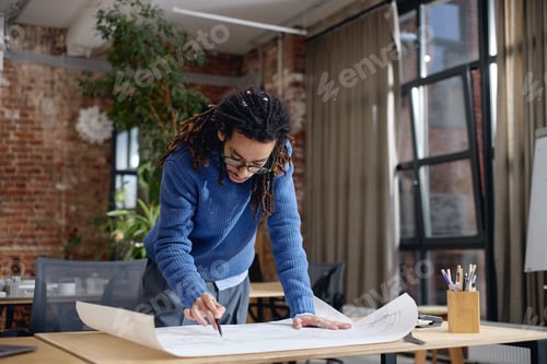 Preview: Young Adult Black Man Analyzing Construction Plans While Standing in Office
