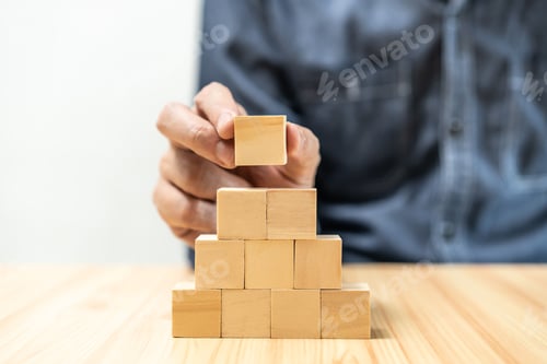 Preview: man in blue shirt placing a cube between wooden blocks on a table