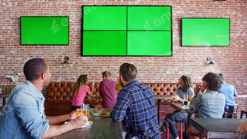 Preview: People Sitting At Tables In Sports Bar Watching Game On Green Screens