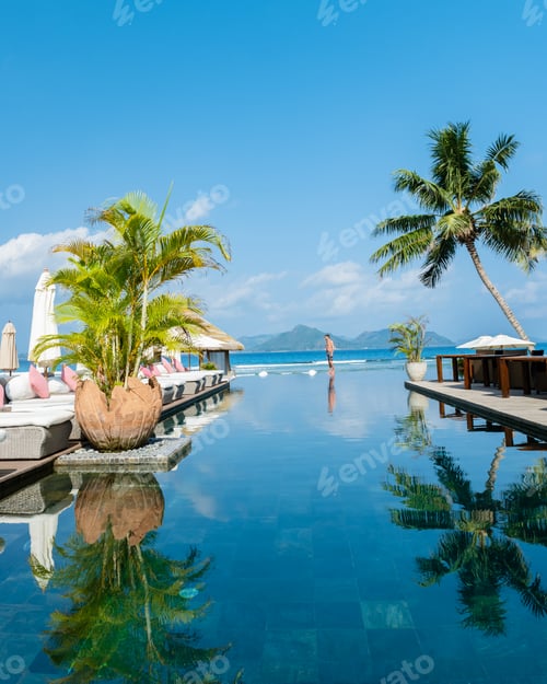 Preview: men at a swimming pool at a luxury hotel with a view over the ocean
