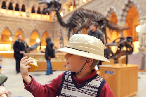 Preview: Little boy scout in safari hat laughs in the Oxford University Museum of Natural History