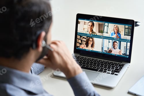 Preview: Indian business man wearing headset having virtual team meeting on video call.
