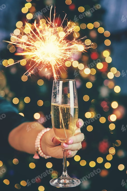 Preview: Champagne in hand against the background of the Christmas tree. Selective focus.