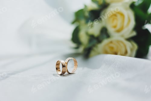 Preview: Precious gold rings for newlyweds on a background of flowers. Wedding rings for a couple.