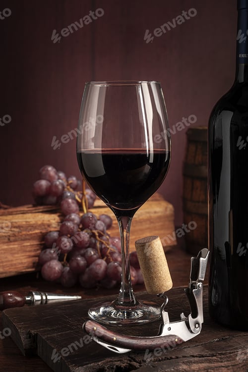 Preview: Glass of red wine near the bottle on a wooden table with grapes