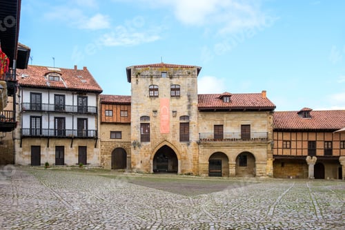 Preview: An old building in the medieval town of Santillana del Mar features a prominent clock tower in its c