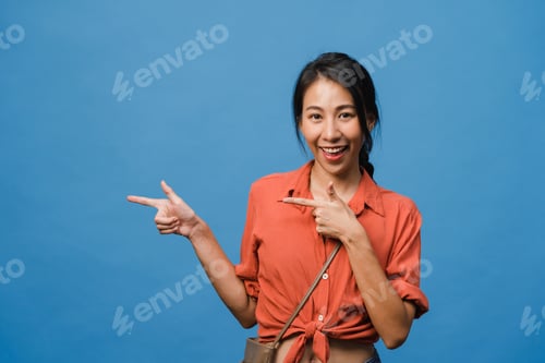 Preview: Asian lady smiling with cheerful expression, shows something amazing at blank space.