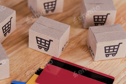 Preview: Credit card and cardboard box with a shopping cart logo on wood table.