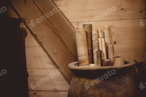 Preview: Closeup of parchment rolls in a clay pitcher under the lights with a blurry background