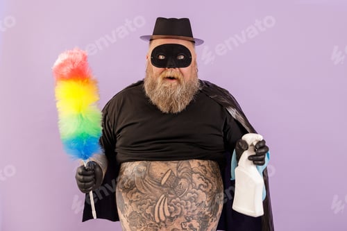 Preview: Emotional plump man in hero suit holds brush and spray bottle on purple background
