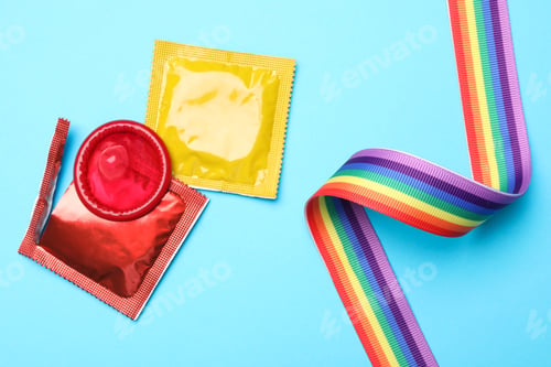 Preview: Colorful condoms and rainbow ribbon on light blue background, flat lay. LGBT concept