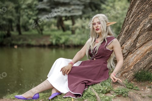 Preview: Young elf girl with blond long hair. Medieval elven princess in a burgundy dress in the forest