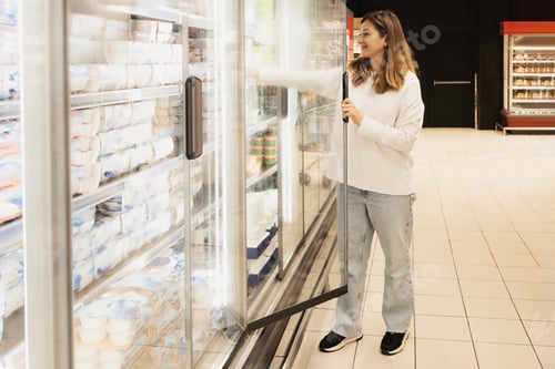 Preview: A woman opens the refrigerator door at a supermarket to select a yogurt.
