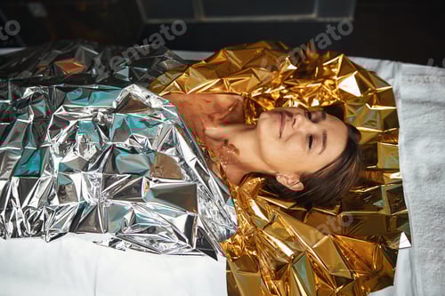 Preview: Happy smiling positive female enjoy spa procedure while wrapping around with foil in spa center
