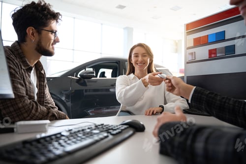 Preview: Car salesman making deal with customers giving keys to new owners in dealership