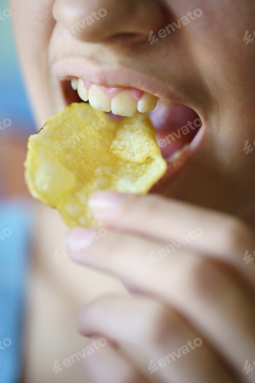 Preview: Unrecognizable teenage girl eating crunchy potato chip