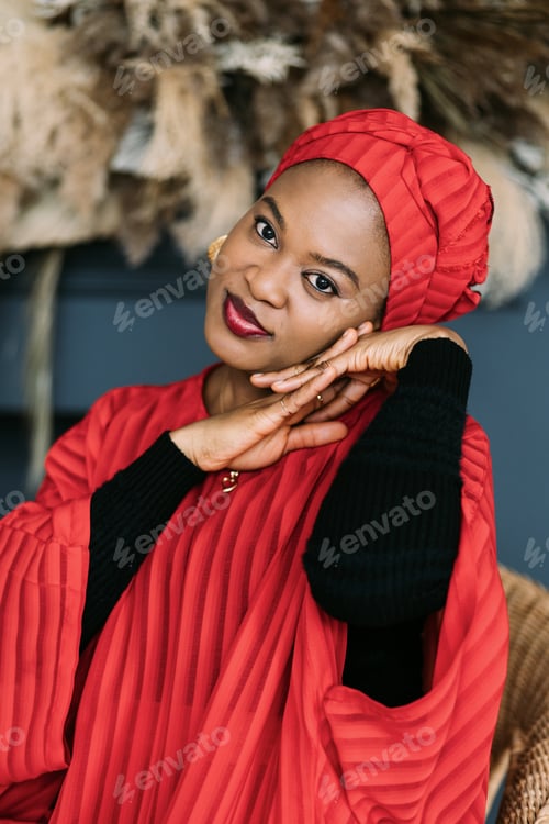Preview: Romantic cute african woman, wearing stylish red dress and headwrap, posing on studio dark