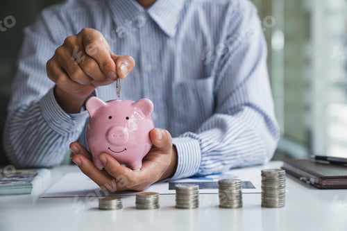 Preview: Businessman with a coin in a piggy bank along with pressing the calculator and writing down savings