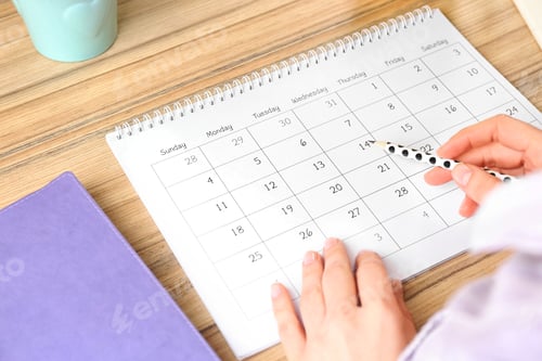 Preview: Woman with calendar at wooden table in office, closeup