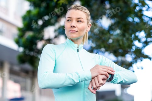 Preview: A beautiful athlete watching her watch on a sunny day