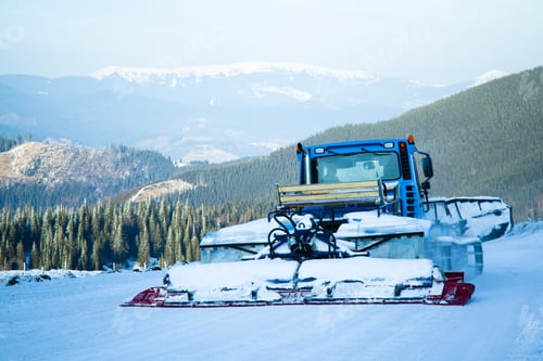 Preview: Snow blower machine working in ski resort with forest and mountains at background