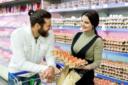 Preview: A young family, a man and a woman choose eggs in a large supermarket.
