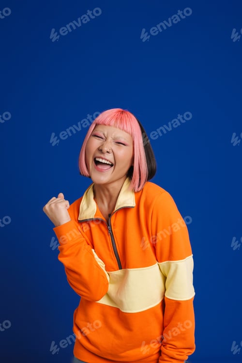 Preview: Asian girl with pink hair screaming while making winner gesture