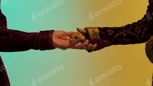 Preview: Close up for eastern man hand giving a big gold nugget to another man, isolated on green and yellow