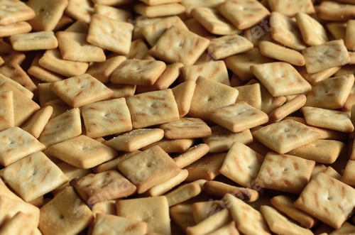 Preview: A lot of small cookies are square shaped. A pattern of a yellow salt cracker