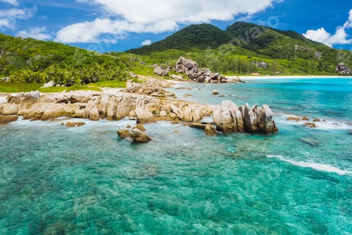 Preview: Old coral reef in the white sand beach on secluded beach of grand anse, La Digue, Seychelles. Aerial