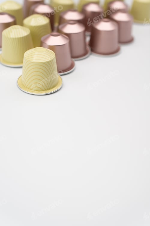 Preview: Vertical shot of white espresso capsules a white background
