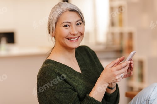 Preview: Photo of woman typing on smartphone and smiling while sitting