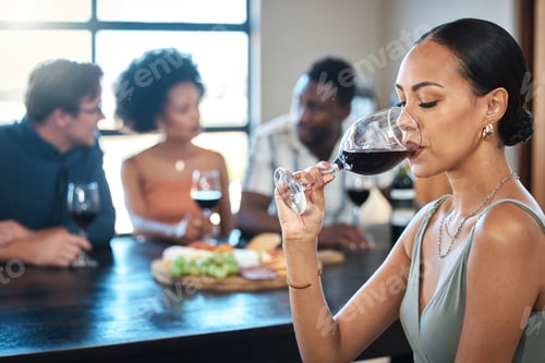 Preview: A woman drinking a glass of wine at a dinner table with friends in a restaurant and enjoying the lu