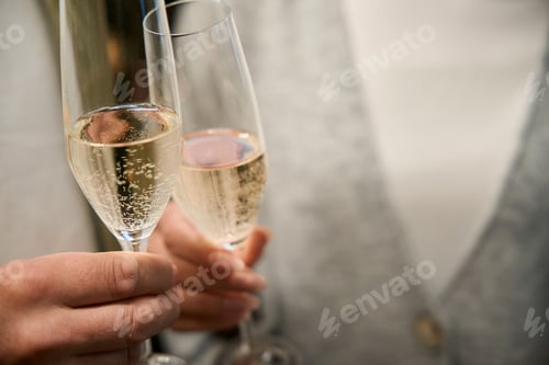 Visualização: Vista de perto de uma jovem mulher e um homem tilintando taças com champanhe durante o Natal