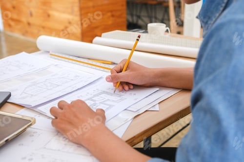 Preview: Architect and engineer drafting blueprints with a pencil and ruler at a work desk