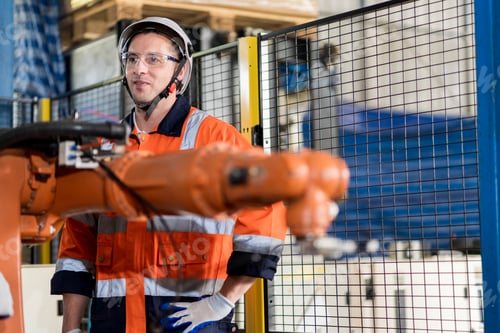 Preview: A team of male engineers meeting to inspect computer-controlled steel welding robots