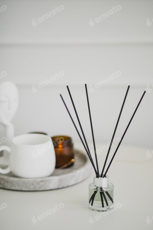 Preview: Still life with white mug, aromatic sticks and candles on a table in a cozy living room.