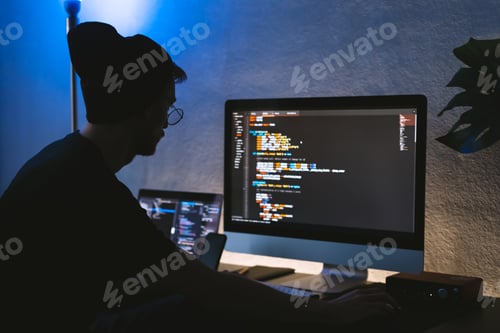 Preview: Young man mobile developer writes program code on a computer, programmer work in home office.
