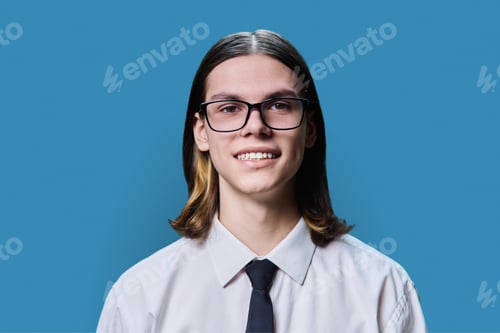 Preview: Headshot portrait of smiling teenage guy on blue studio background