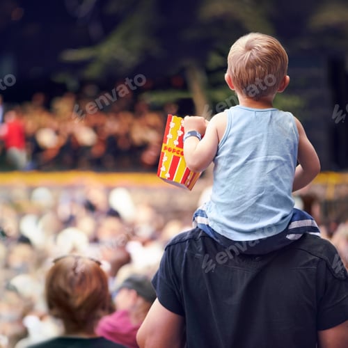 Preview: Rearview shot of a young boy sitting on his fathers shoulders at an outdoor festival