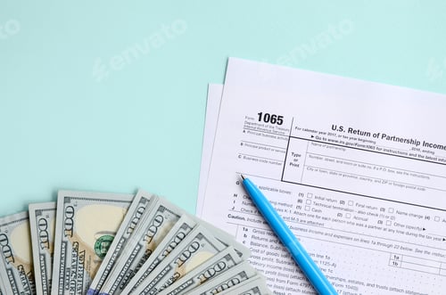 Preview: 1065 tax form lies near hundred dollar bills and blue pen on a light blue background