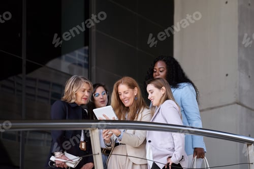 Preview: Outdoor meeting: Businesswomen reviewing statistics on tablet