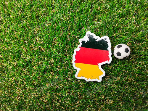 Preview: A ball and German flag sticker is on a green field.