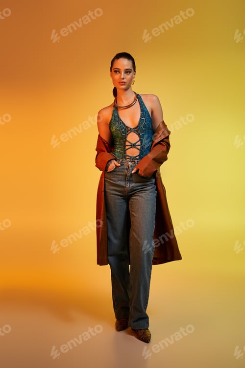 Preview: Fashionable young woman highlights stunning snake print attire against a bright yellow background.