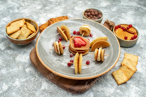 Vista previa: Top view of fruit pancakes biscuits and cakes for breakfast on cutting board on blue background
