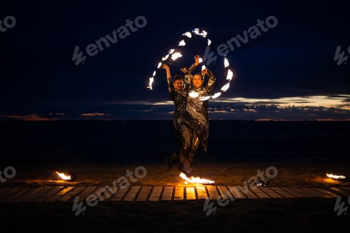 Preview: Two girls light a sparkler on the beach at dusk.