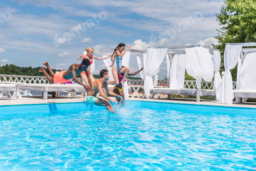 Preview: Group of beautiful young multiethnic people looking happy while jumping into the swimming pool