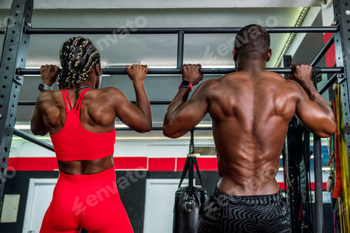Preview: Two black bodybuilders athletes in a sports gym doing a barbell back exercise