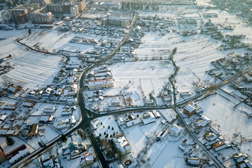 Preview: Aerial view of private homes with snow covered roofs in rural suburbs town area in cold winter